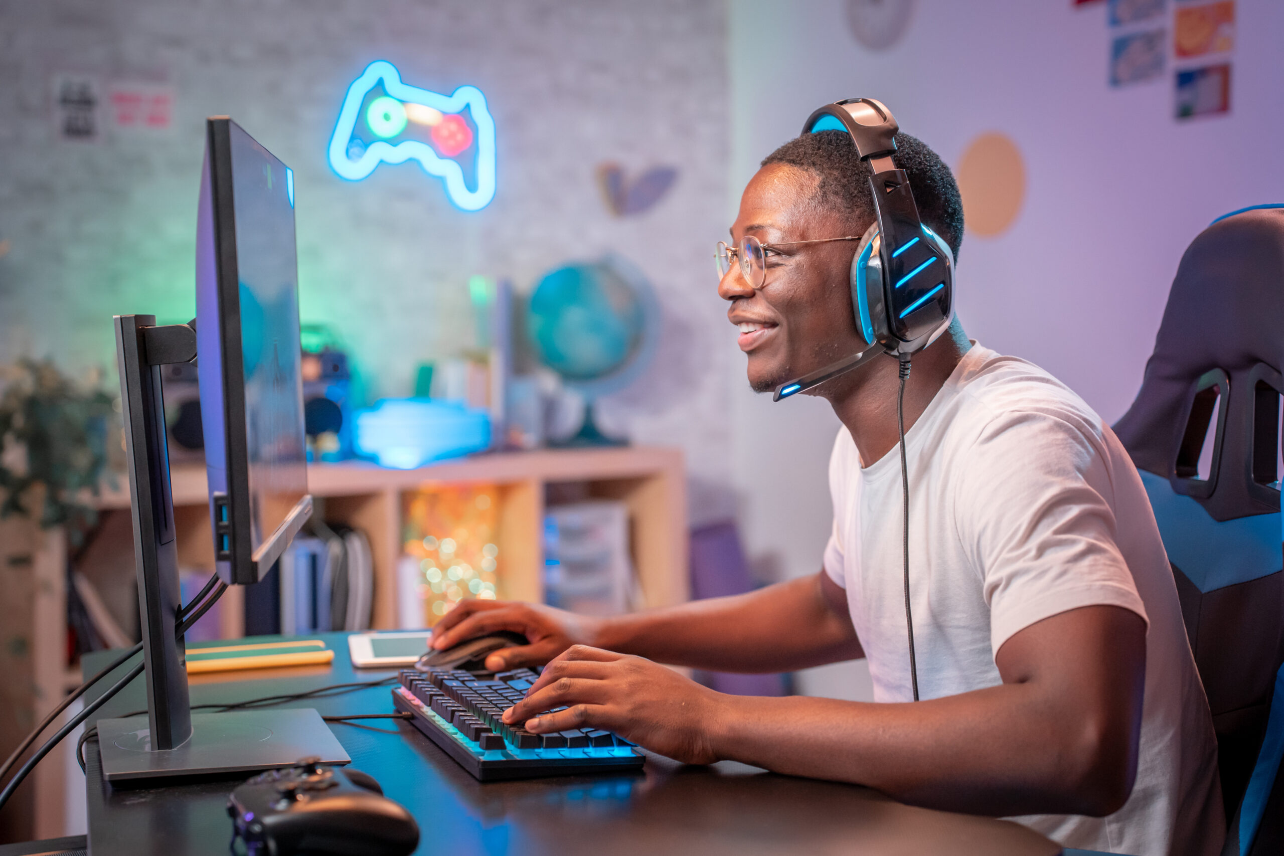 Streamer young man professional gamer play online games computer with headphones, colorful neon light room. Man vor PC der Spiel streamt