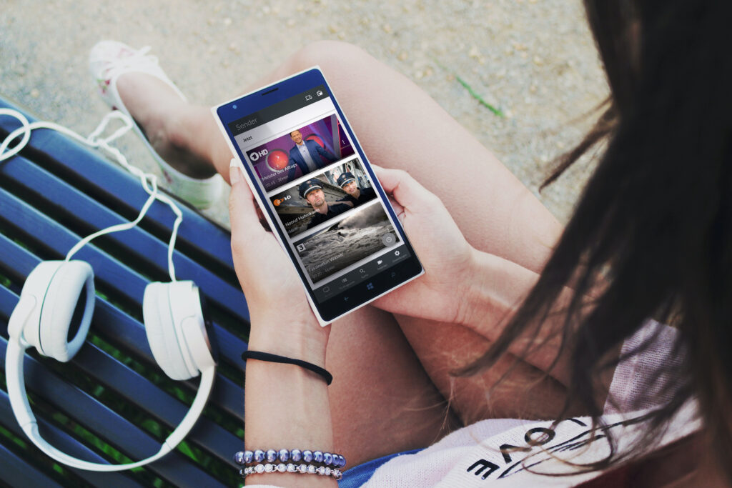 TV Fellow unterwegs 2 Frau die sich auf ihrem Handy das Fernsehprogramm ansieht